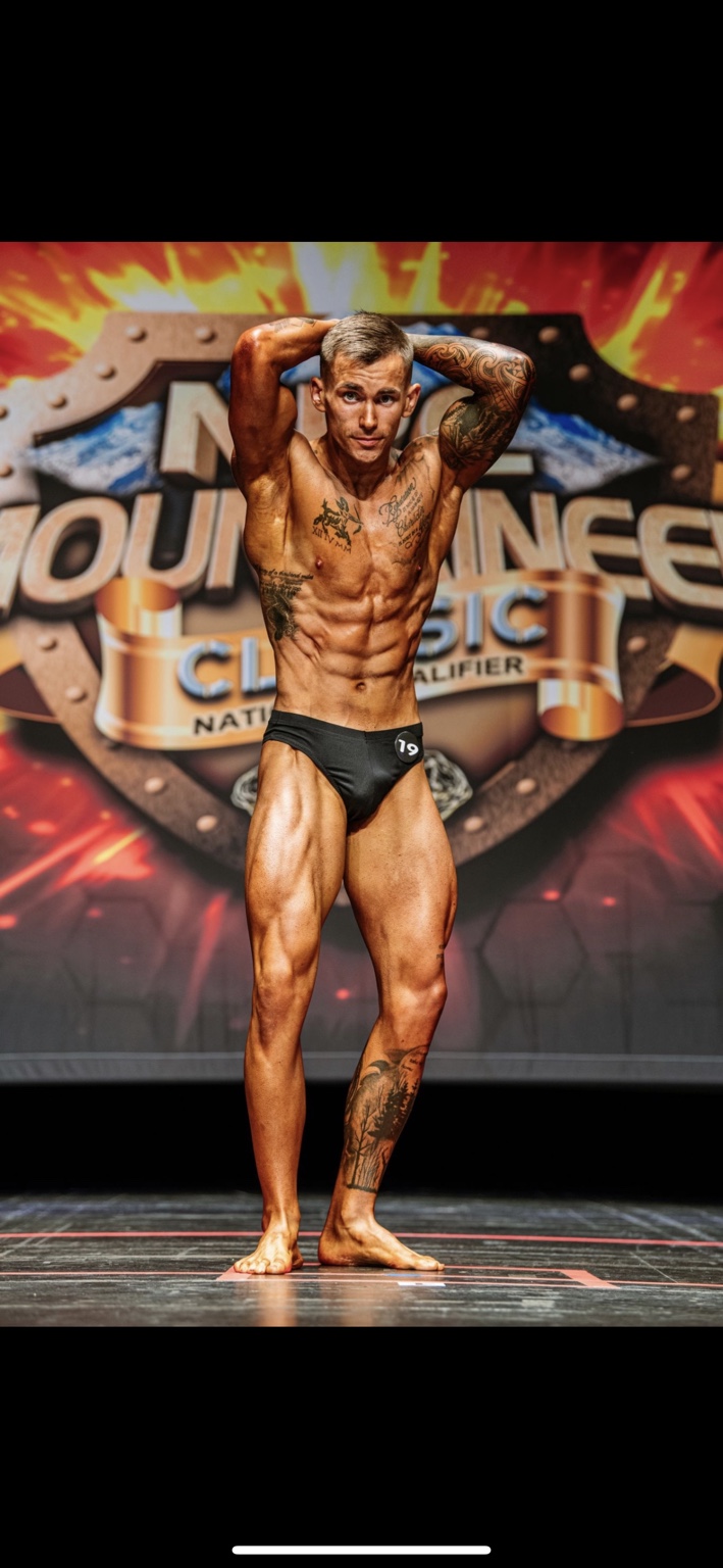 Jake posing on stage at a bodybuilding competition