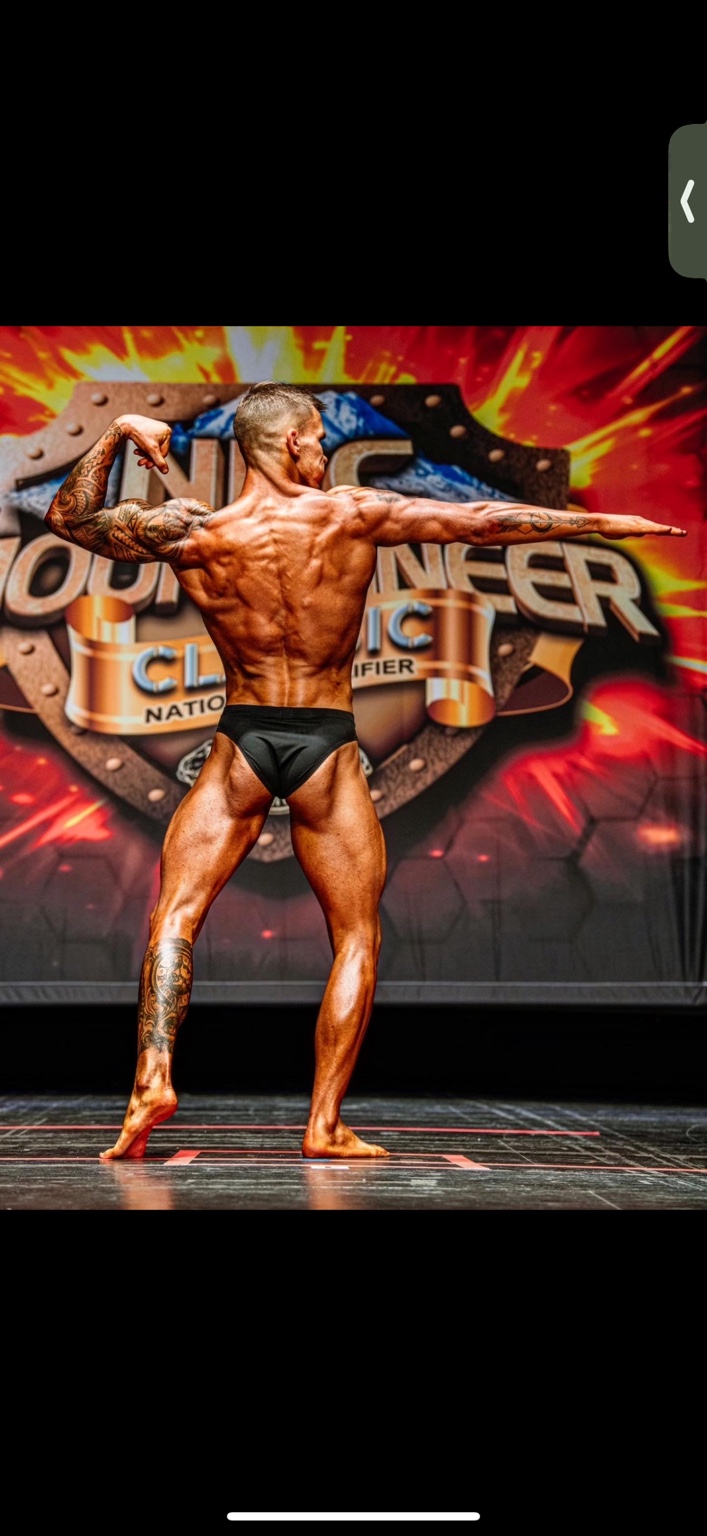 Jake showing a back pose at a bodybuilding competition
