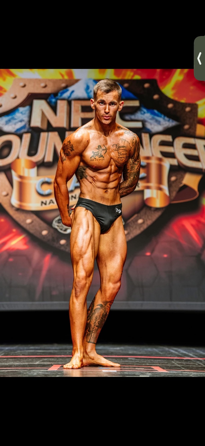 Jake posing on stage at a bodybuilding competition